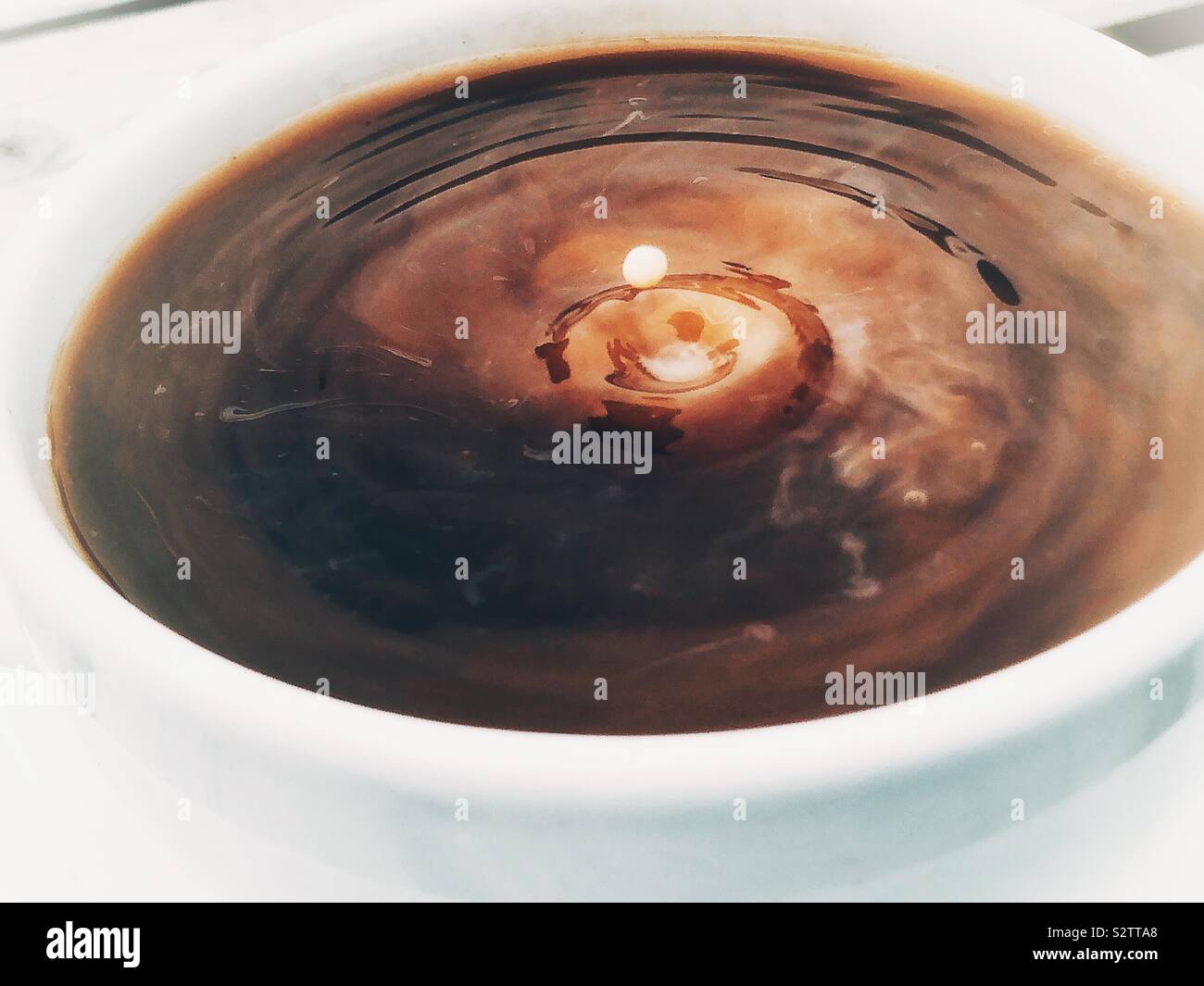 Goccia di latte in un moto vorticoso tazza di caffè Foto Stock