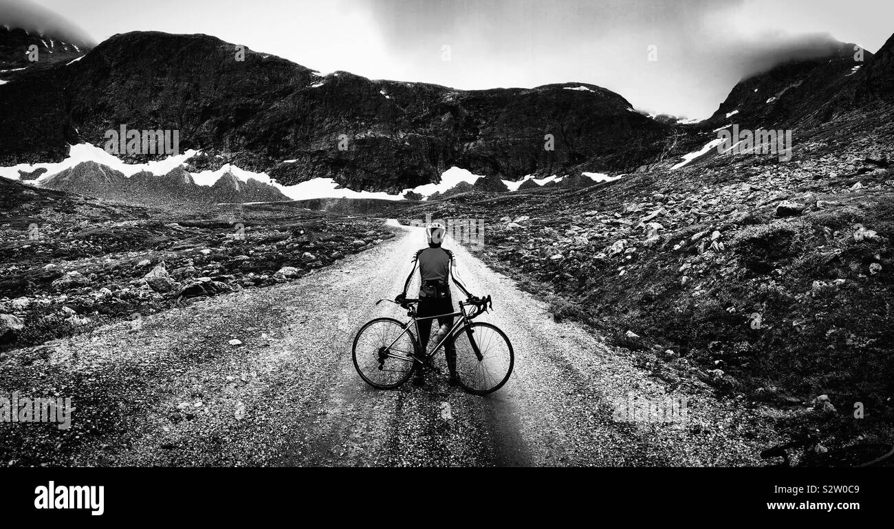 Femmina ciclista su strada di ghiaia, Romsdal, Norvegia Foto Stock