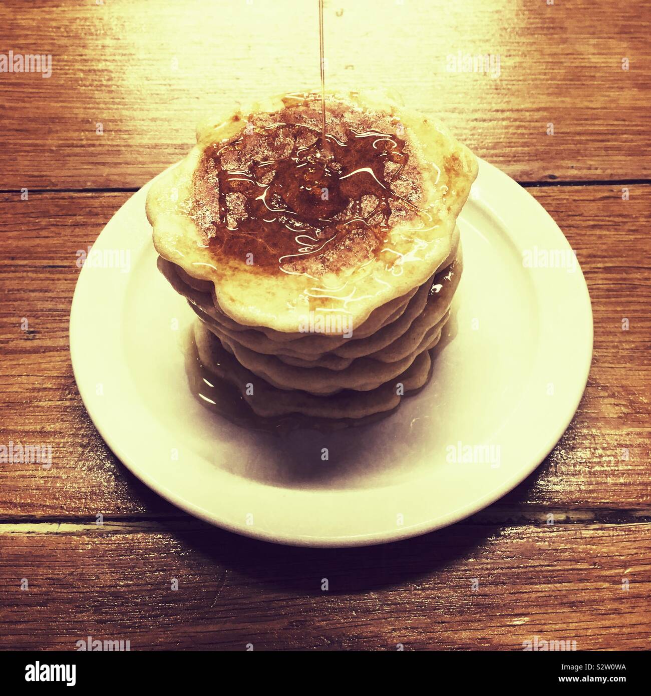 Pila di latticello pancake con sciroppo essendo riversato su di loro. Foto Stock