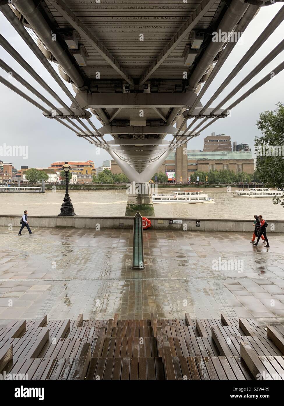 London, Regno Unito - 12 August 2019: sotto il ponte downtown, sotto la pioggia. Millennium Bridge attraverso il fiume Tamigi. - Immagine stock catturata con smartphone