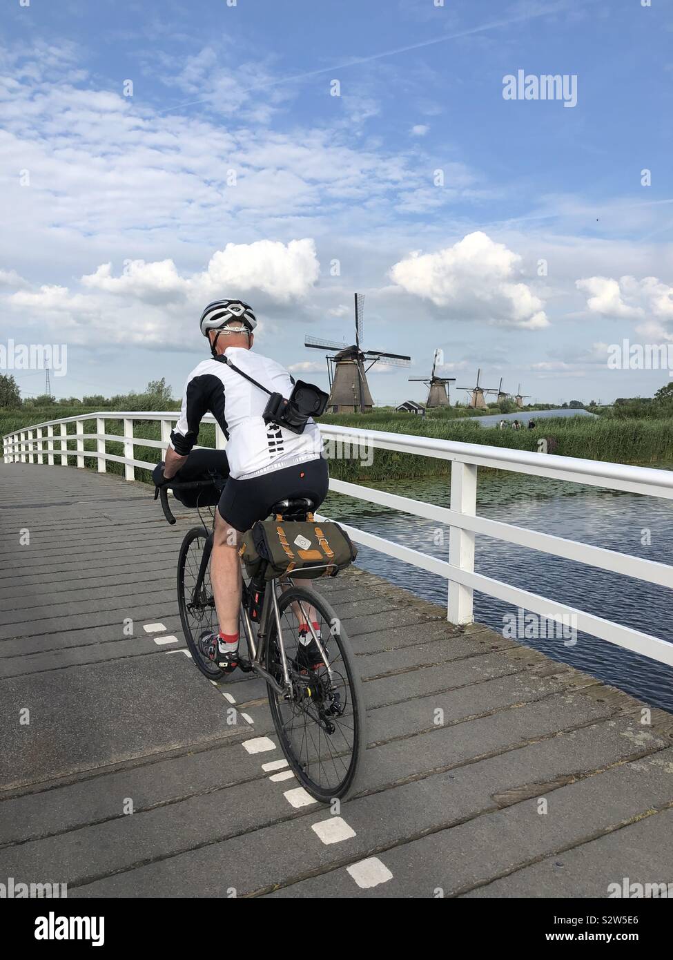 Ciclista maschio a cavallo su ponte a Kinderdijk sito UNESCO, Paesi Bassi. Foto Stock