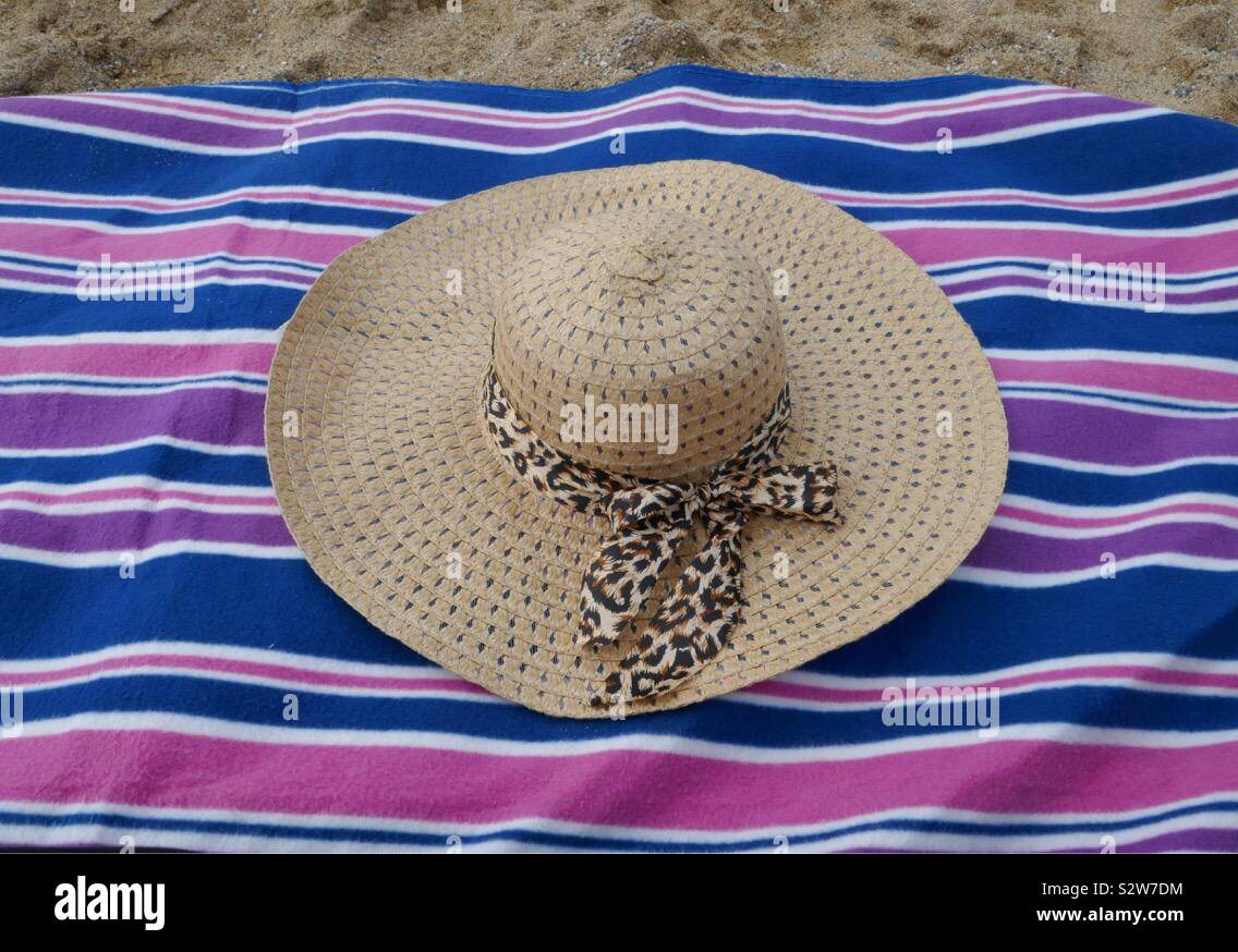 Cappello per il sole con nastro su una rosa e blu Coperta picnic sulla spiaggia. Foto Stock