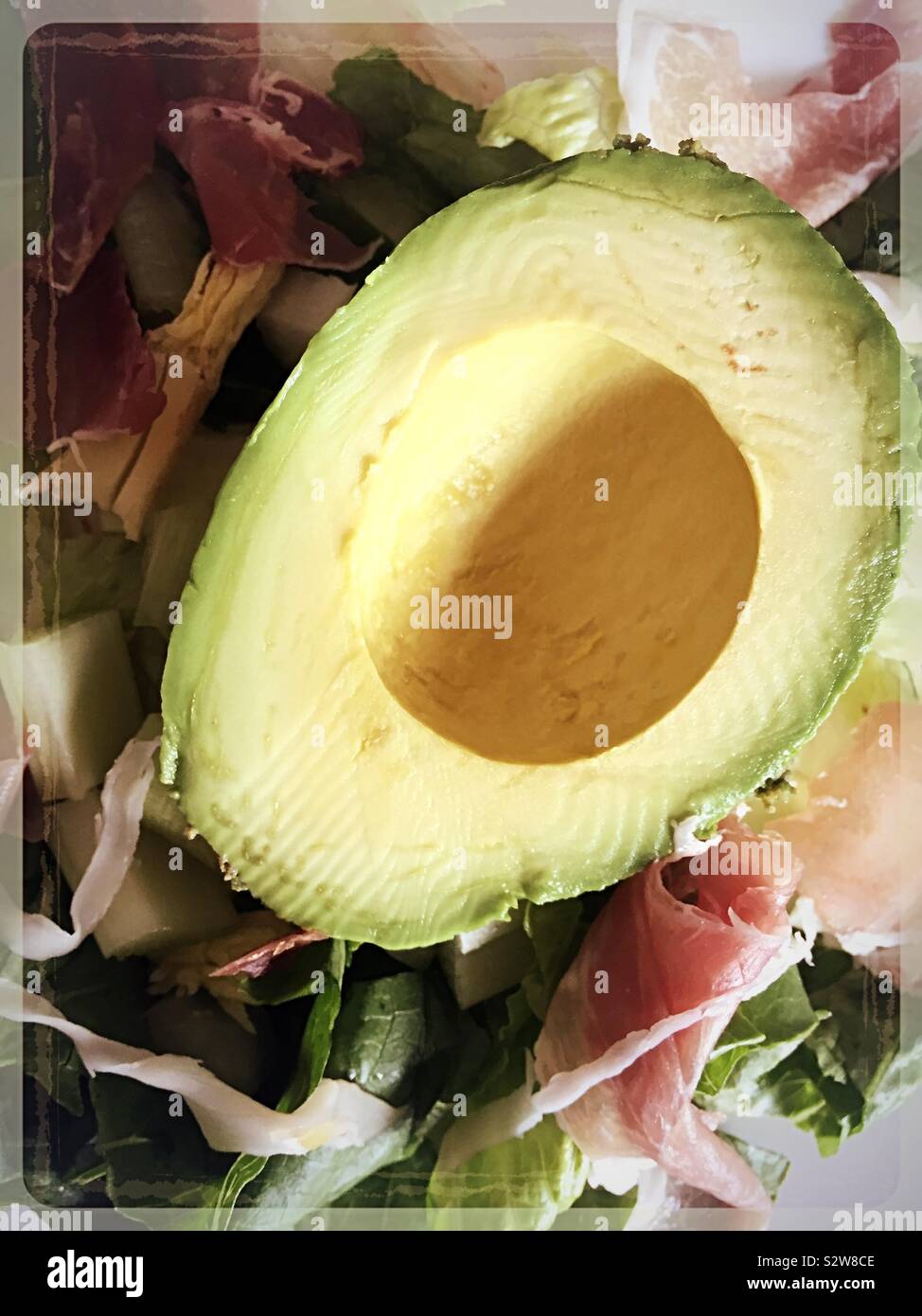 Gioco piatto particolare di una metà di avocado su una fresca insalata estiva Foto Stock