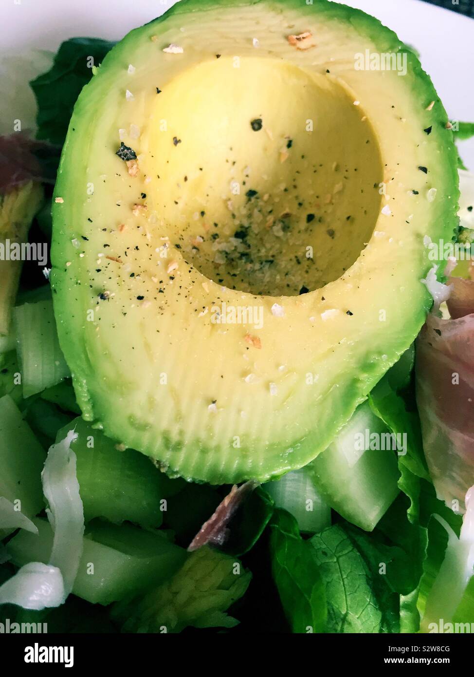 Vicino la piana di laici un avocado semi stagionato su una insalata Foto Stock