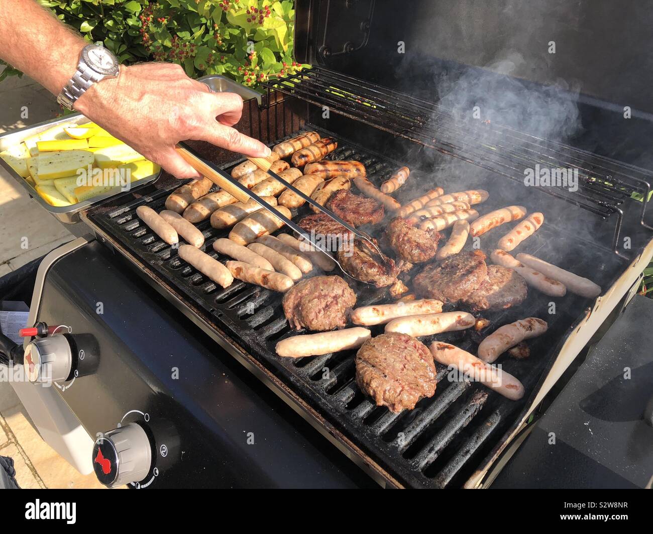 Salsicce e hamburger cottura su un grill all'aperto Foto Stock