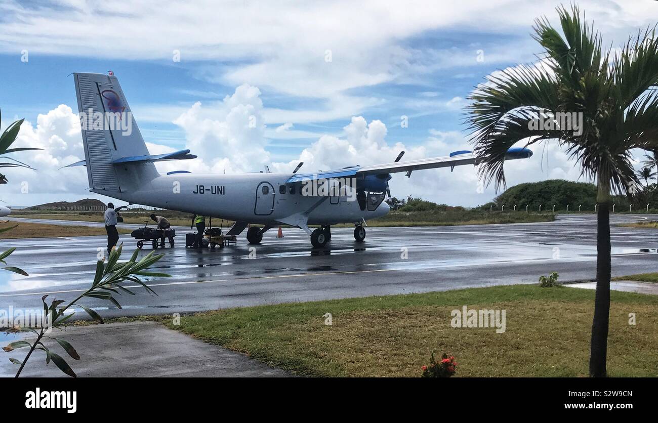 Grenadine Airlines aereo essendo caricati sull'asfalto bagnato da tre uomini pronti per la partenza da Union Island - St.Vincent e le Grenadine Foto Stock
