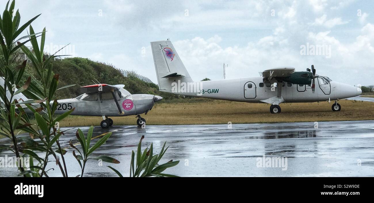 Due aeroplani a Union Island Aeroporto accanto a un asfalto bagnato la pista - St.Vincent e le Grenadine Foto Stock