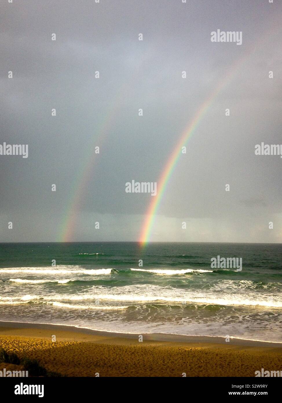 Brillante arcobaleno doppio sopra l'oceano a Coolum Beach vicino a Noosa sulla Sunshine Coast, Queensland, Australia Foto Stock