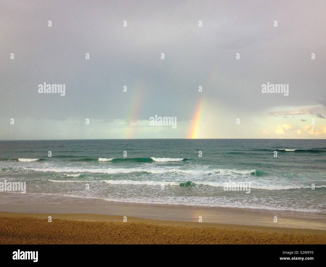 Luminose twin rainbows oltre oceano dopo una tempesta a Coolum Beach vicino a Noosa sulla Sunshine Coast, Queensland, Australia Foto Stock