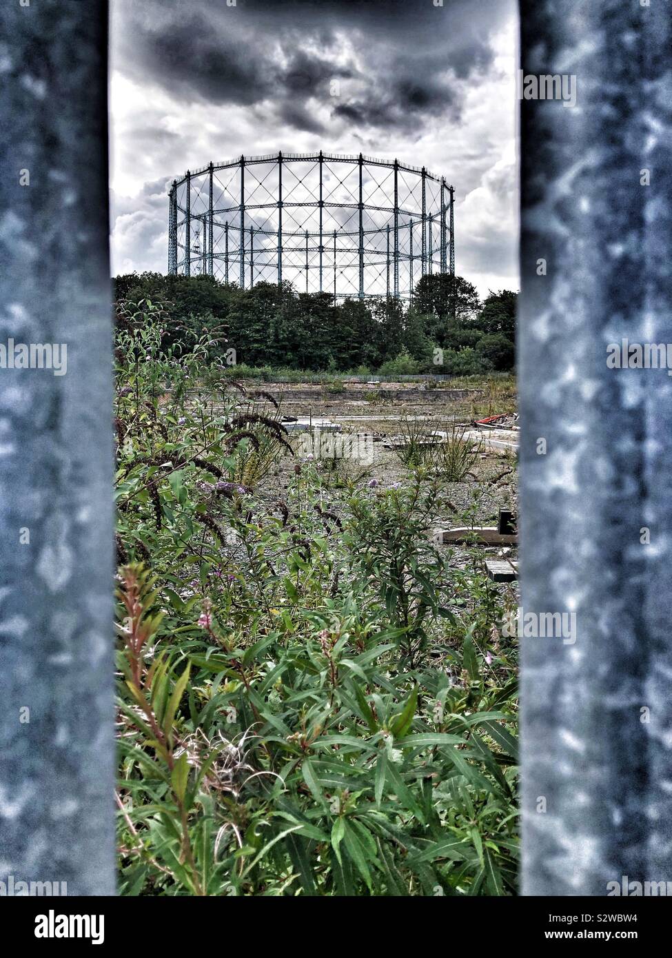 Titolare del gas visto attraverso la recinzione e wasteground Foto Stock