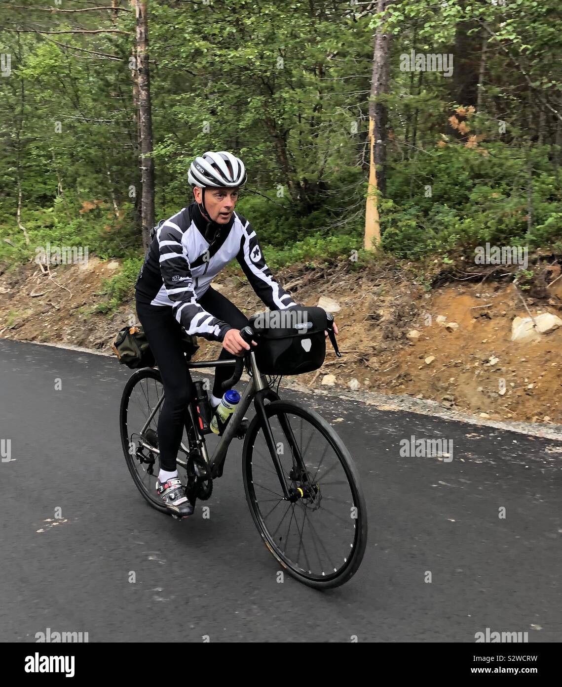 Ciclista maschio salire ripida collina nella valle Romsdal, Norvegia Foto Stock