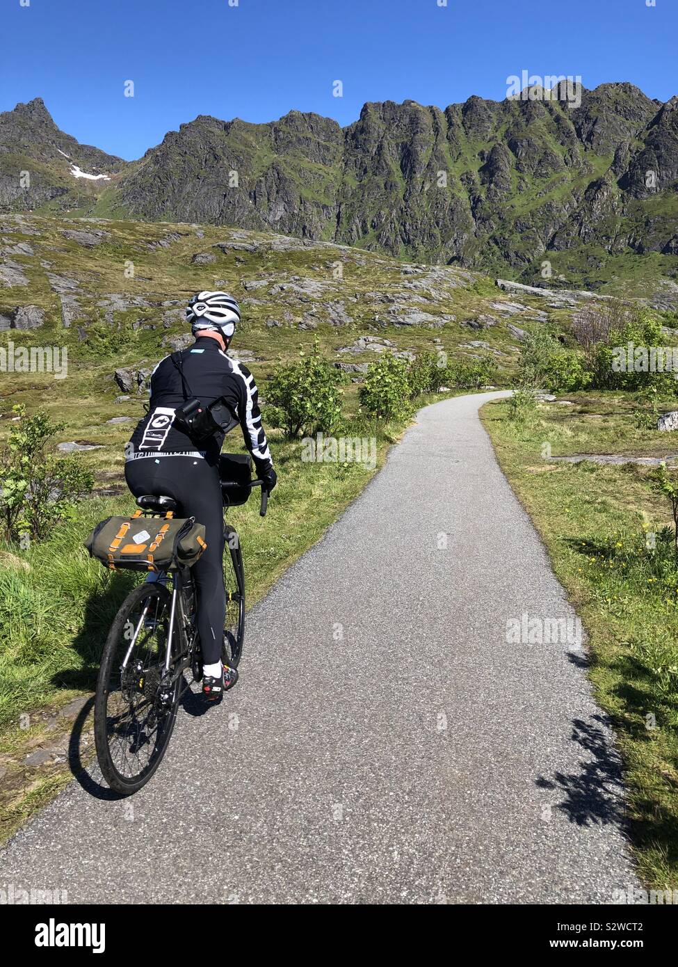 Maschio ciclista pedalando attraverso le isole Lofoten in Norvegia. Foto Stock
