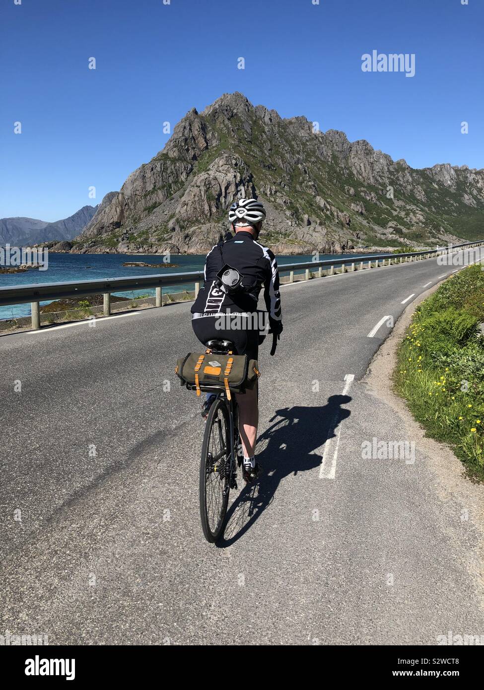 Ciclista maschio a cavallo lungo la strada per Henningsvaer, Isole Lofoten in Norvegia Foto Stock