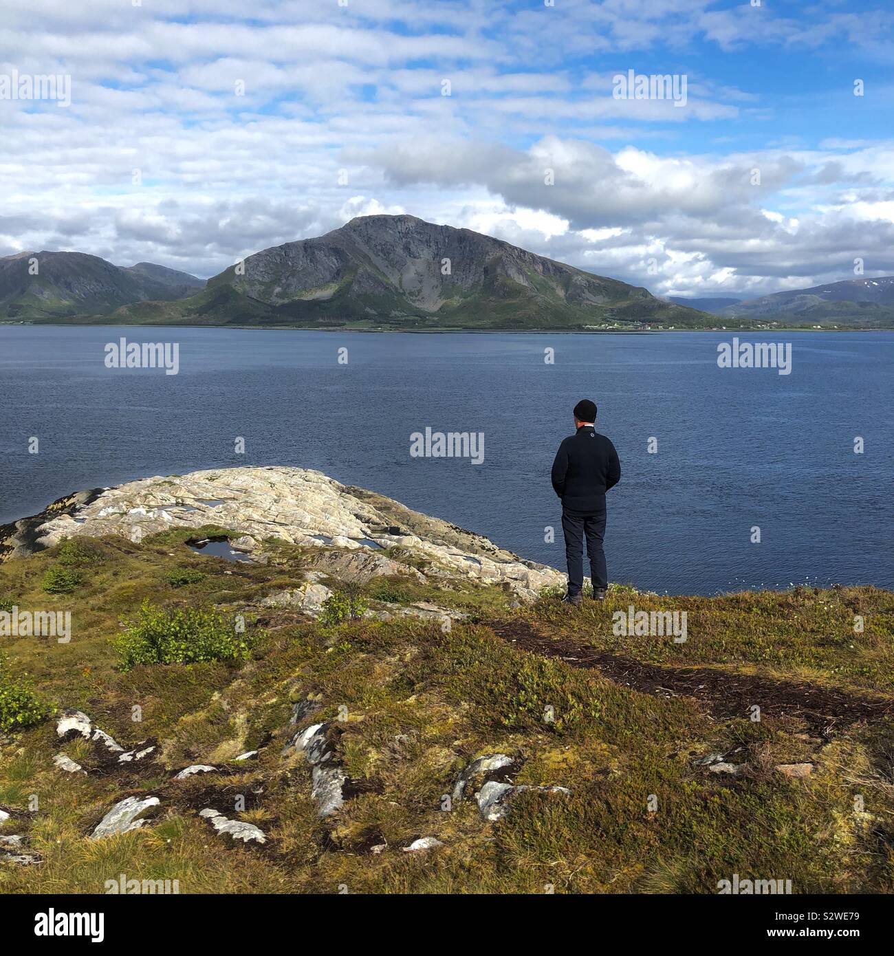 Uomo che guarda fuori attraverso un fiordo, Bronnoysund, Norvegia Foto Stock