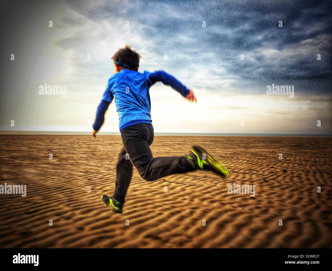Ragazzo correre sulla spiaggia nel Regno Unito Foto Stock