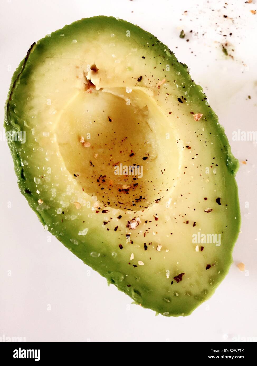 Piatto di laici una metà di avocado condito con sale e pepe bianco un tagliere - Immagine stock catturata con smartphone