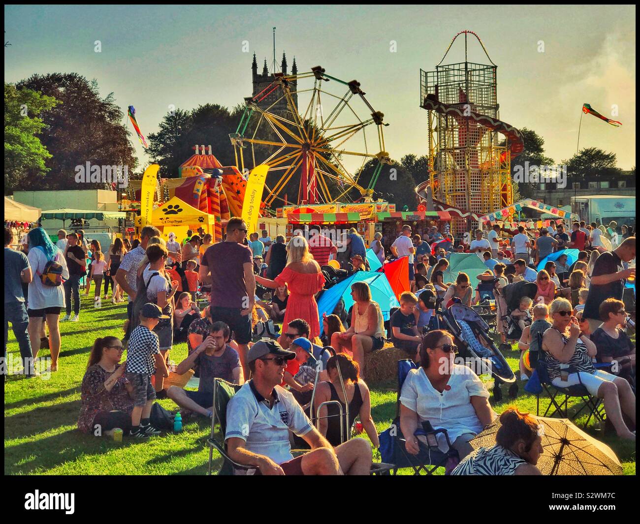 Un grande gruppo di persone che godono l'atmosfera di un weekend di vacanza a un festival. Ascoltare la band dal vivo, potrete crogiolarvi al sole, giro la ruota panoramica. Credito foto © COLIN HOSKINS. - Immagine stock catturata con smartphone