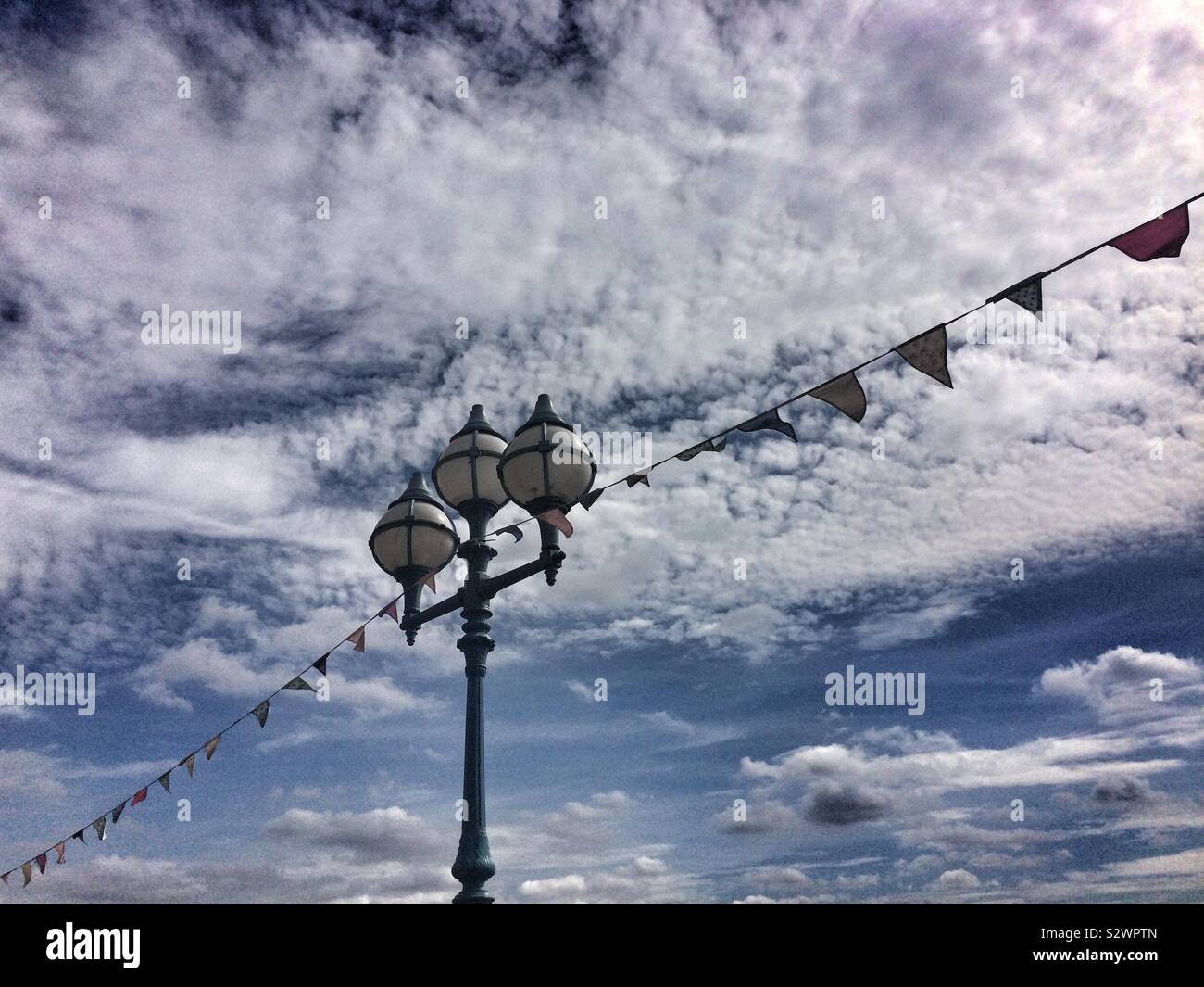 Decorativo di illuminazione stradale e bunting contro un cielo drammatico, London, Regno Unito Foto Stock