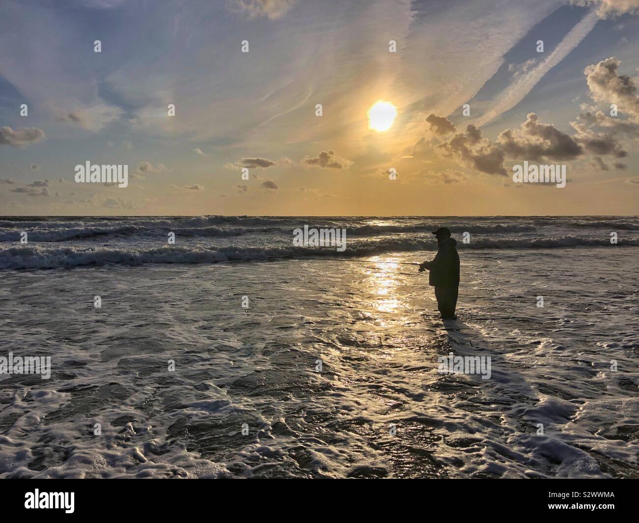 Il pescatore pesca di bass nel surf a Llangennith, Gower, Swansea, South West Wales, Agosto. Foto Stock