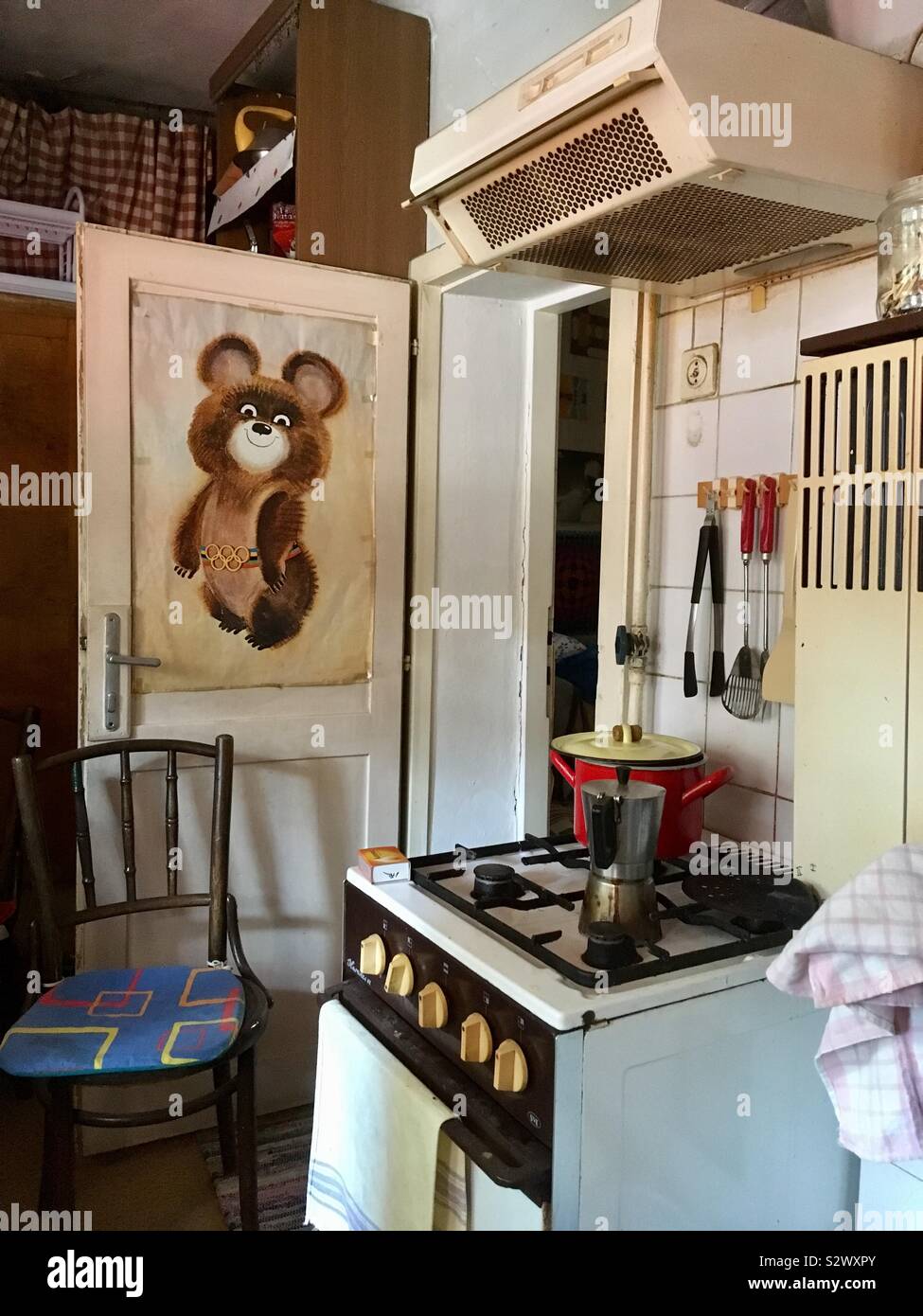 Retrò cucina con fornello a gas, estrattore e di un grande poster di Misha l'orso russo mascotte del 1980 Giochi olimpici di Mosca (XXII Giochi Olimpici Estivi) sulla porta Foto Stock