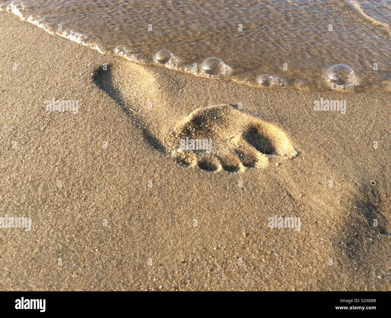 Singola impronta umana sulla spiaggia sabbiosa Foto Stock