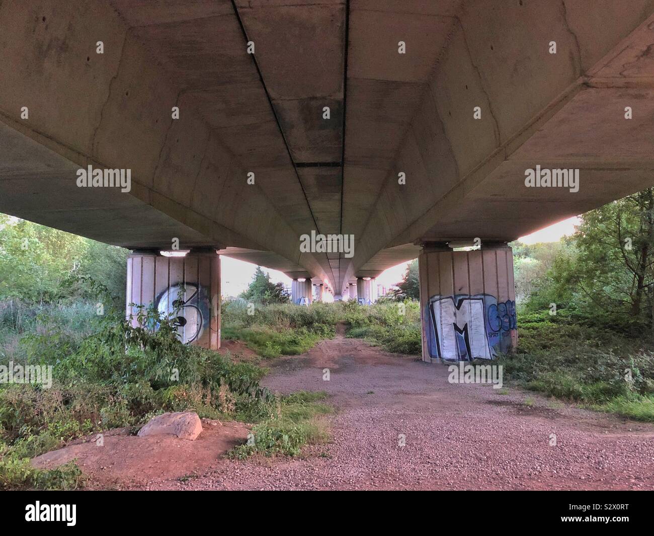 Al di sotto di un ponte stradale con graffitied colonne di supporto. Foto Stock