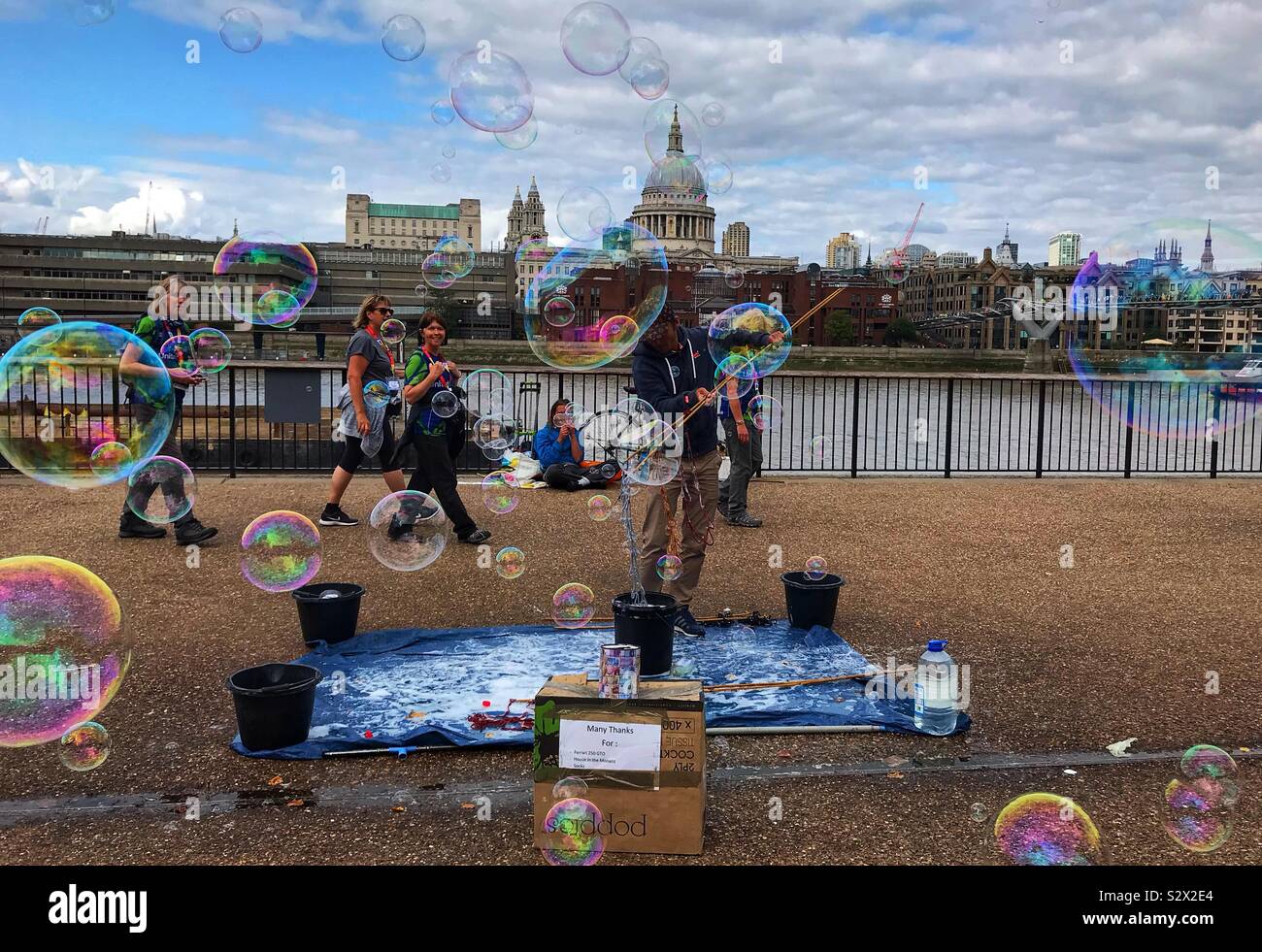 Venditore ambulante/ Busker soffiare bolle accanto al Fiume Tamigi con St.Pauls Cathedral in background - London REGNO UNITO Foto Stock