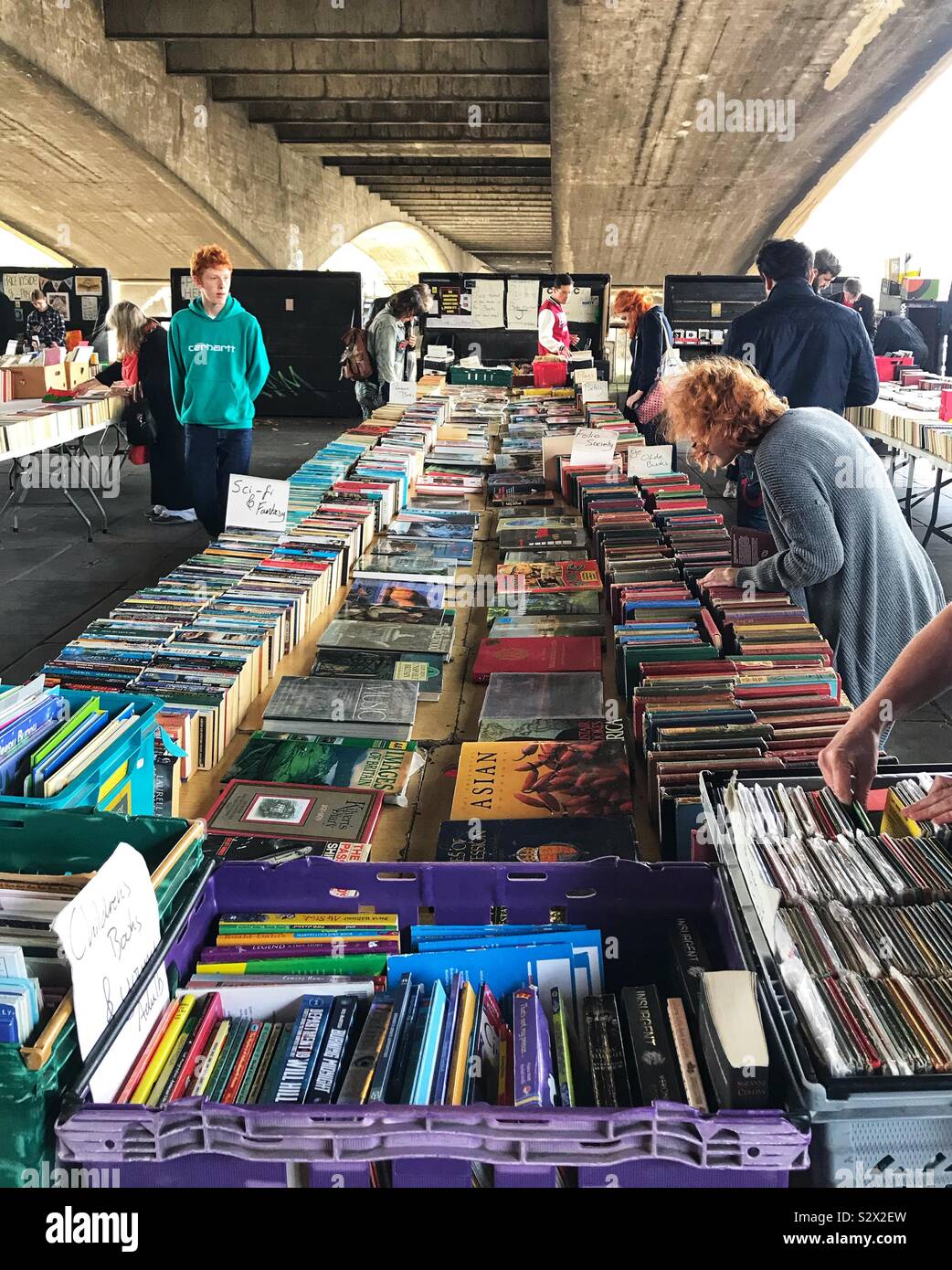 Mercato delle Pulci Prenota stallo con persone che guardano i libri sulle rive del fiume Tamigi sotto un ponte - London REGNO UNITO Foto Stock