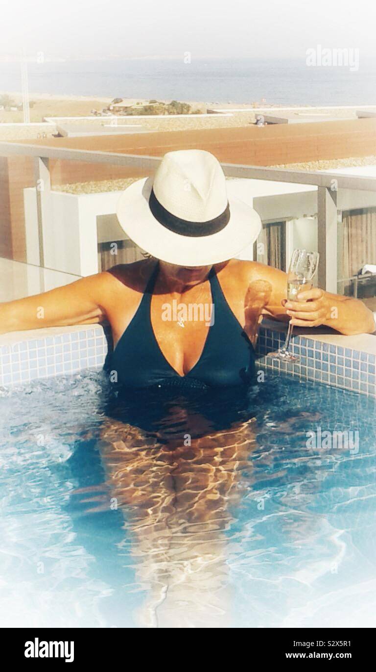 Donna in piscina con un bicchiere di champagne Foto Stock