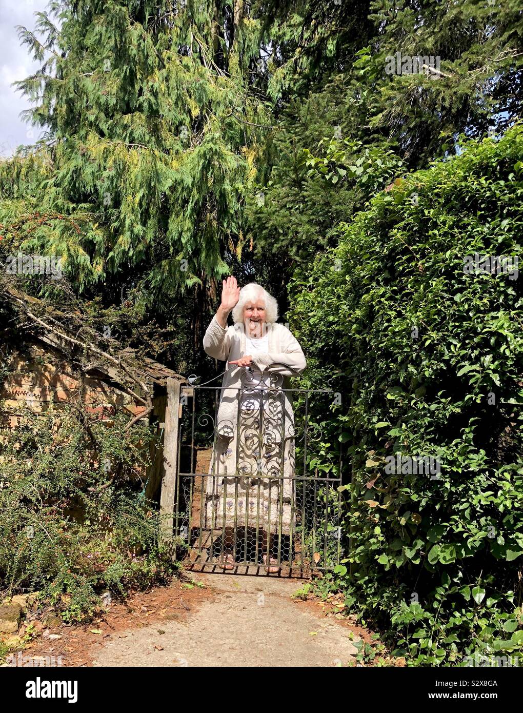 Una signora anziana sventolato addio ai visitatori. Foto Stock