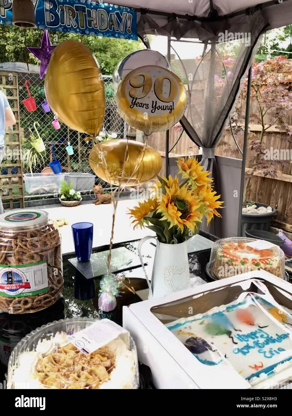 Il novantesimo compleanno palloncini e una fetta di torta sul tavolo Foto Stock