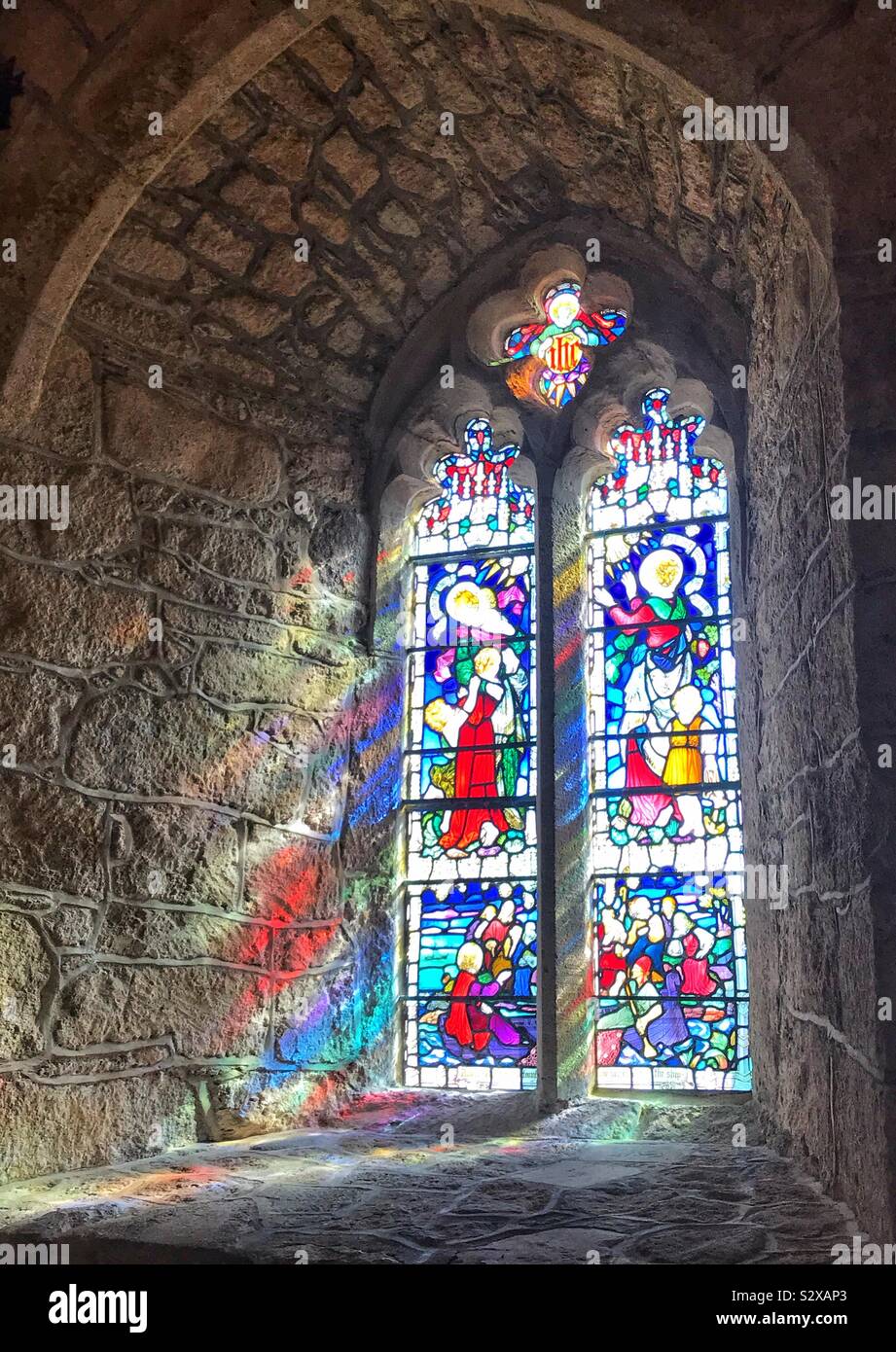 Finestra di Vetro colorato nella chiesa di St.Michael's Mount, Cornwall Regno Unito con la luce che riflette sul muro di pietra Foto Stock
