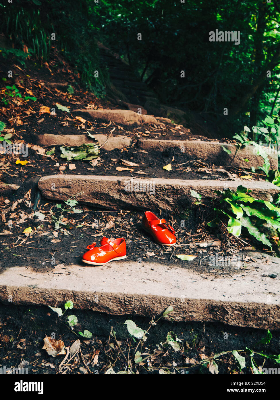 Red scarpe per bambini sui passi nella foresta - Immagine stock catturata con smartphone