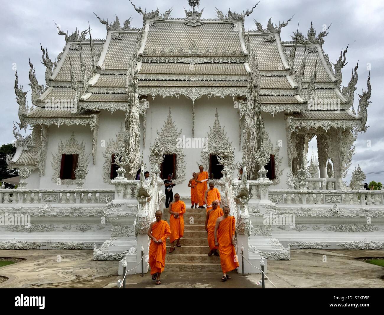 Arancione e bianco: monaci in Wat Rong Khun, Chiang Rai. Foto Stock