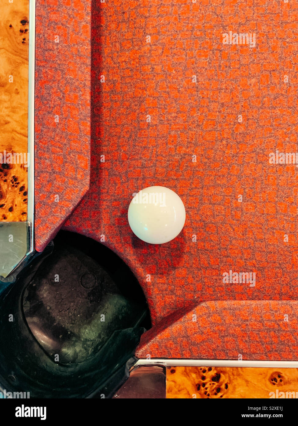 Bianco cue piscina piscina vicino a una tasca su una tabella rossa Foto Stock