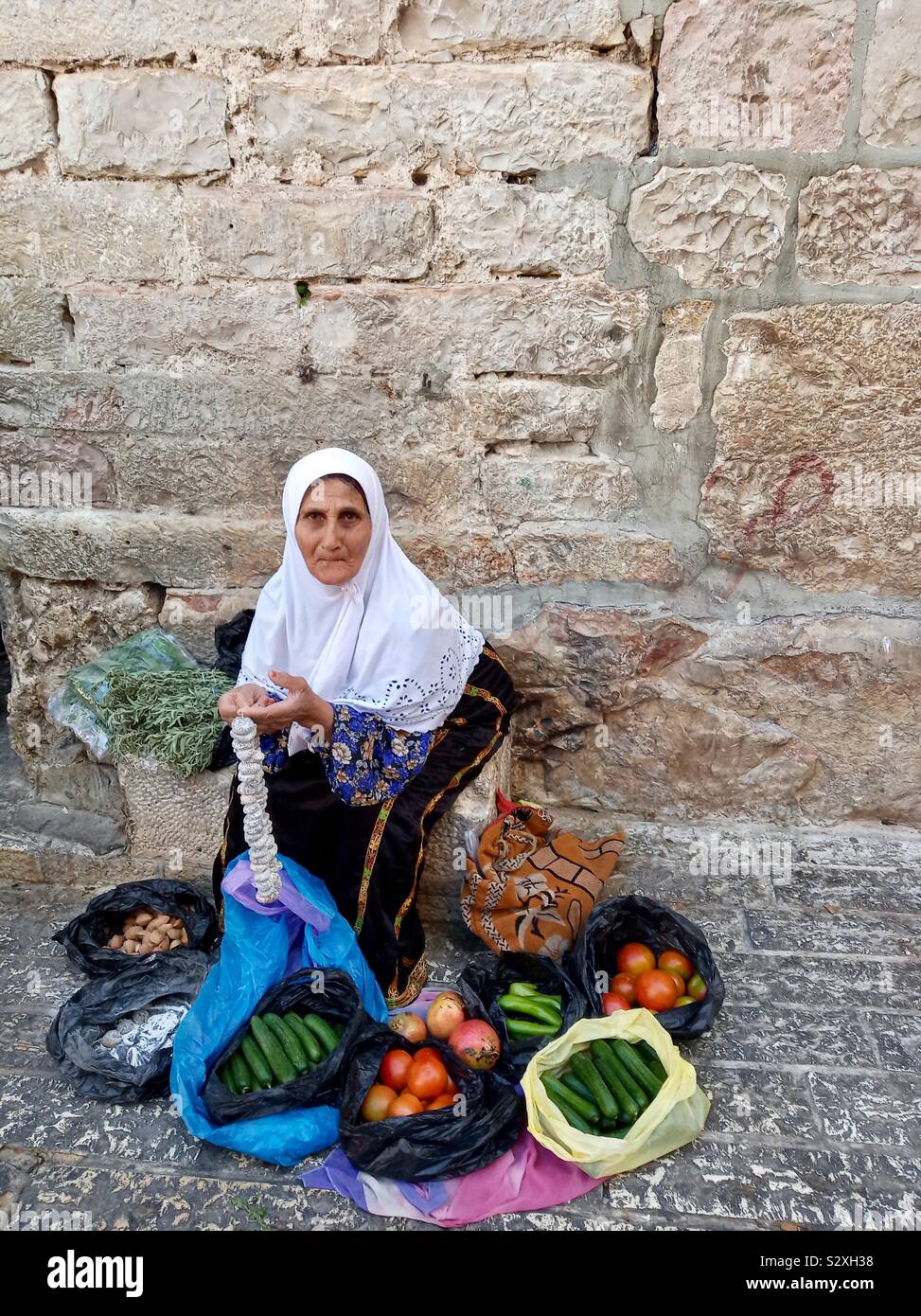 Una donna Palestinese vendita di ortaggi per le strade del quartiere musulmano nella città vecchia di Gerusalemme. Foto Stock