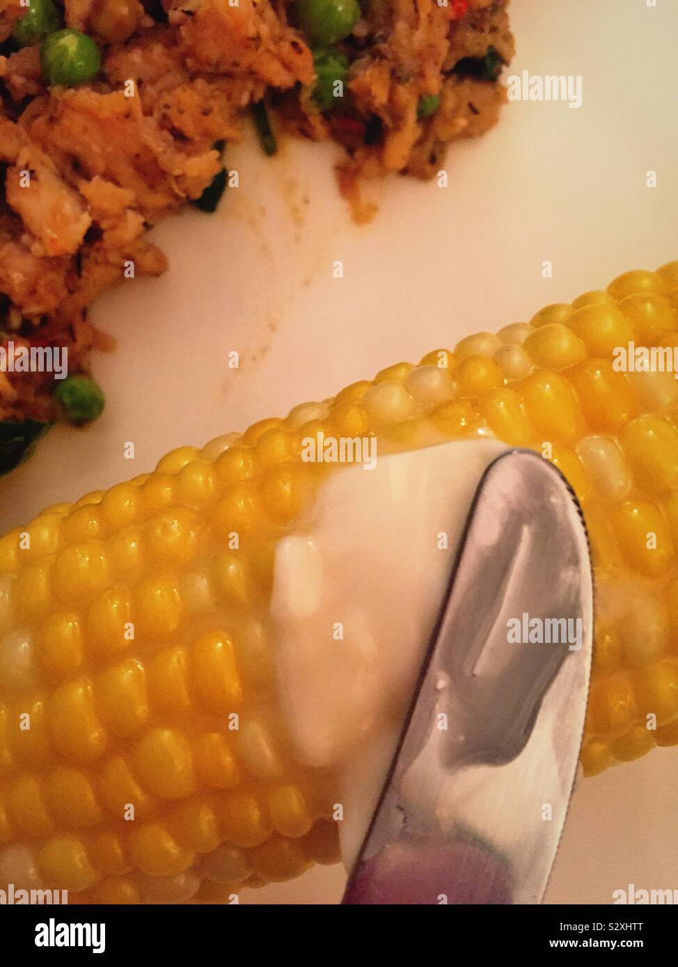 Il burro che viene applicata con un coltello su sulla pannocchia di mais, STATI UNITI D'AMERICA Foto Stock