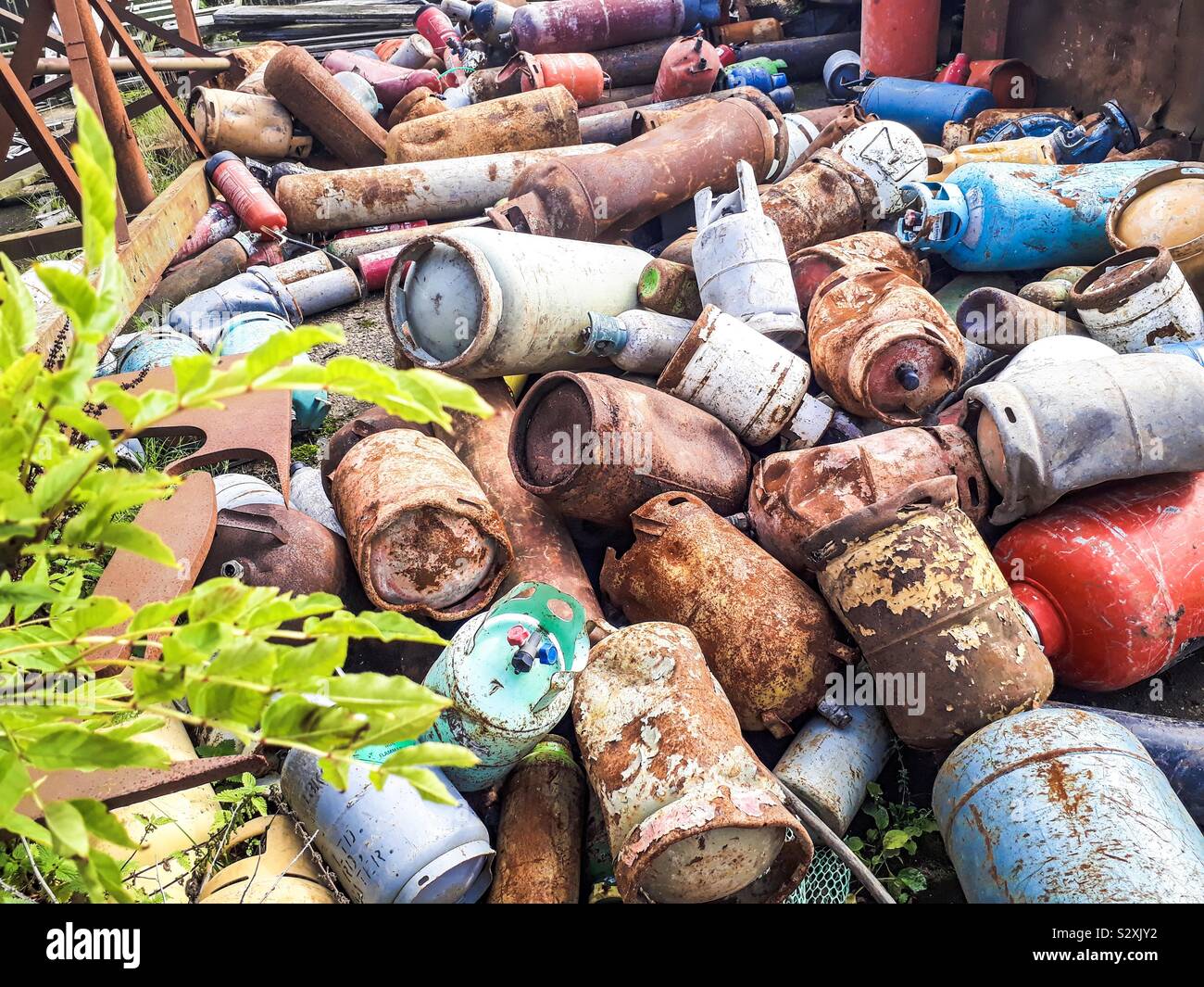 Vecchie e arrugginite le bombole a gas su scrapyard dietro all'albero. Foto Stock