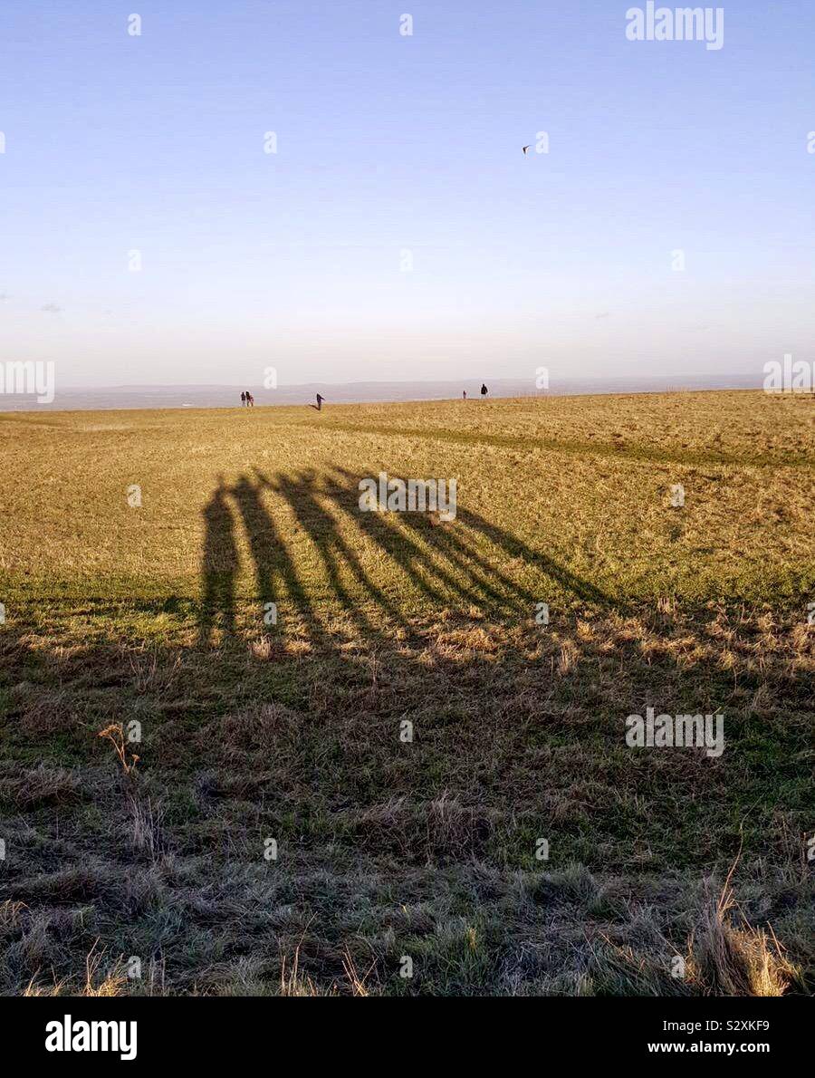 Le ombre di sei persone sono gettati in mezzo alla campagna invernale paesaggio. Foto Stock