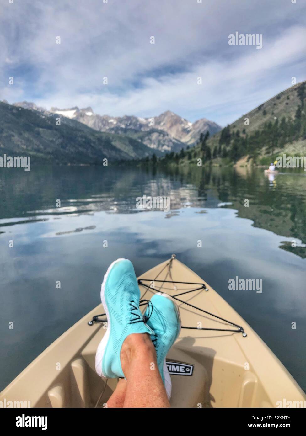 Il kayak sul lago di montagna con un po' di neve sulla cima della montagna.  Blu brillante scarpe da acqua Foto stock - Alamy