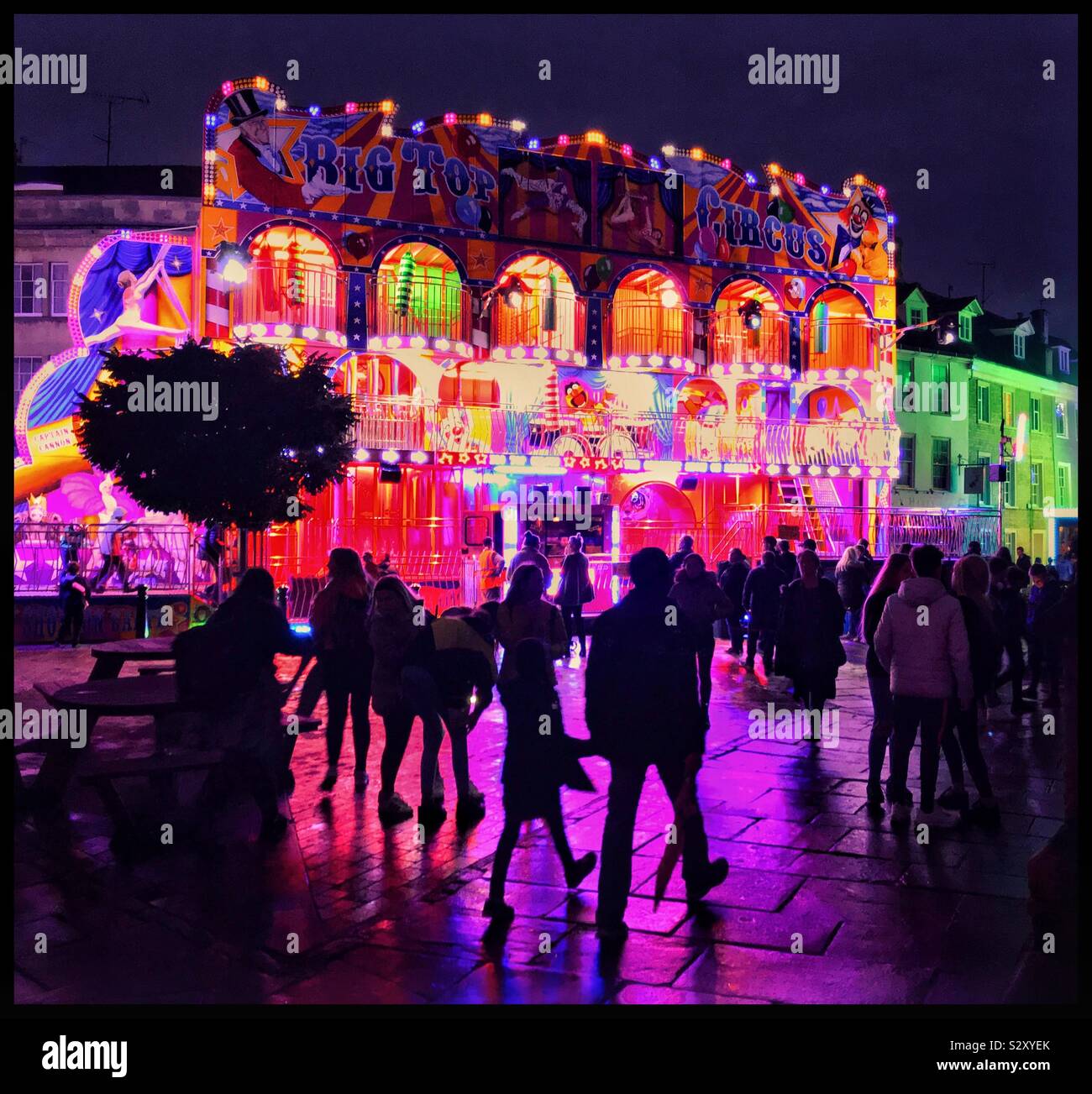 Le sagome delle persone che camminano passato una serata impressionante fiera ride/intrattenimento. Un sacco di colori luminosi. Un sacco di divertimento in fiera. Credito foto - © COLIN HOSKINS. - Immagine stock catturata con smartphone