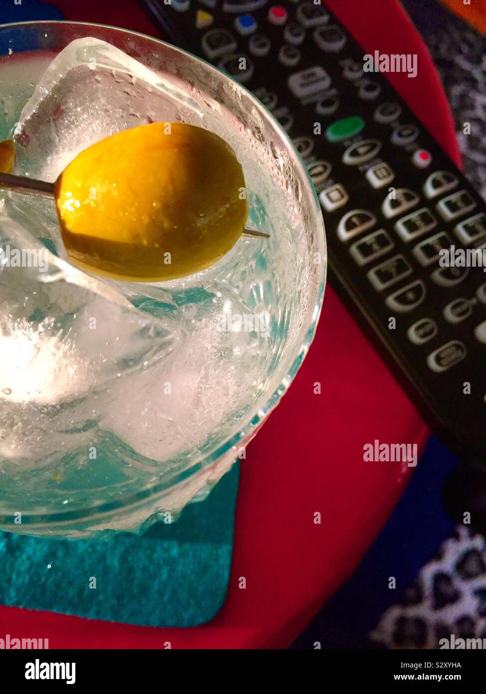 Close up di un martini sulle rocce in un bicchiere di cristallo accanto a un telecomando TV, STATI UNITI D'AMERICA - Immagine stock catturata con smartphone
