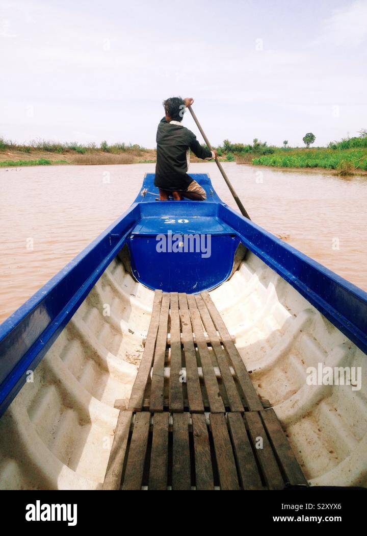 Un ragazzo remare una barca sul fiume Mekong in Cambogia. Foto Stock