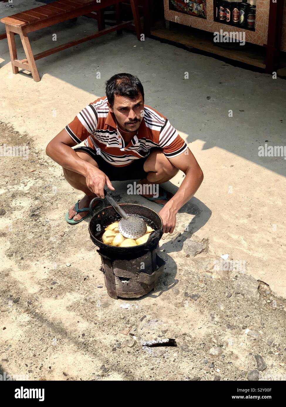 Un uomo la cottura di momo o riempite i panini su un marciapiede in Nepal. Foto Stock