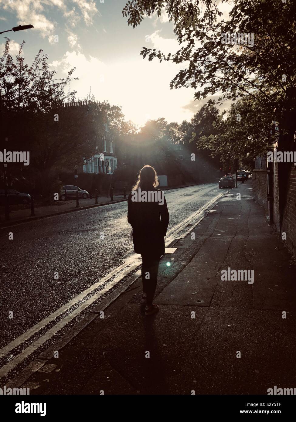 Una donna è a piedi durante il tramonto a Londra Foto Stock