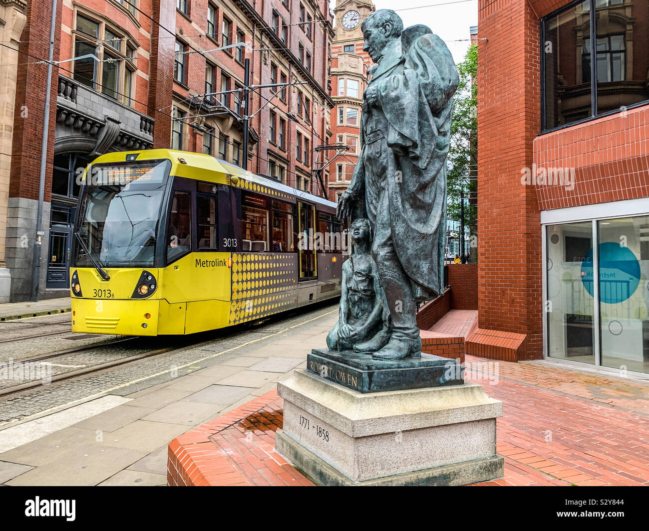 Tram Metrolink di Manchester passando Robert Owen statua Foto Stock