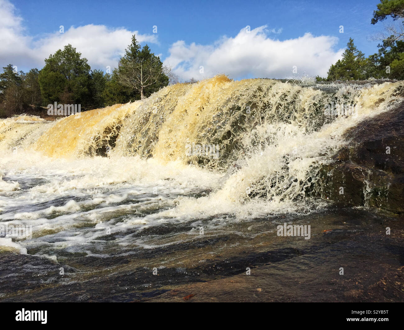 Che scorre veloce cascate e rocce intorno a una piscina esterna parco pubblico in Columbus Georgia USA dopo una forte pioggia. Foto Stock