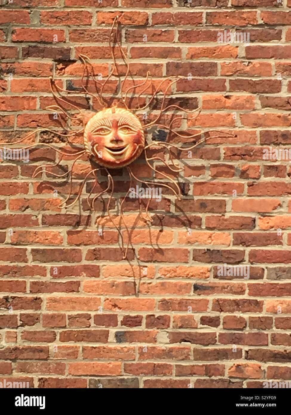Sun faccia su un muro di mattoni Foto Stock