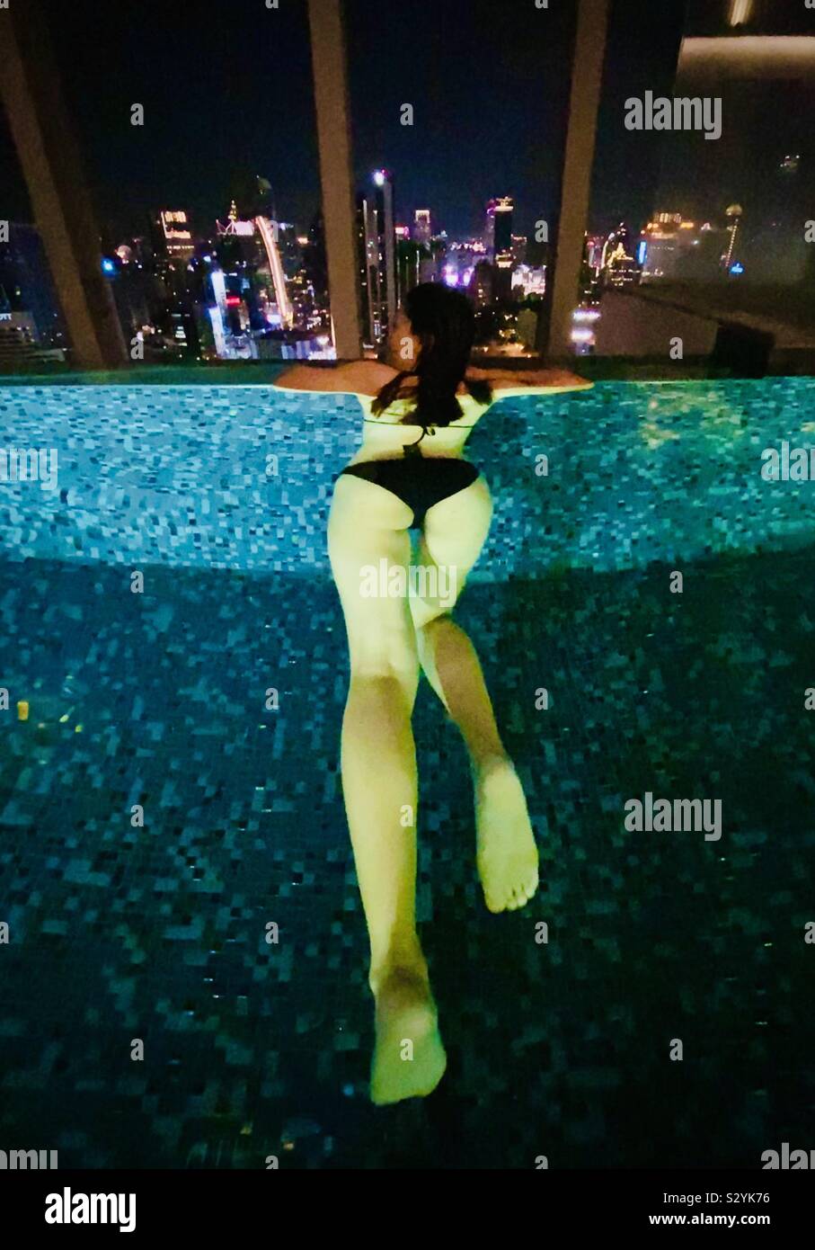 Ragazza in tempo di notte piscina infinity affacciata city Foto Stock