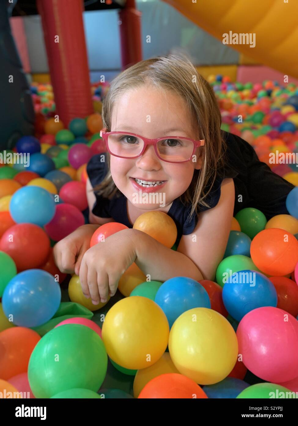 5 anno vecchia ragazza con gli occhiali in una fossa a sfera Foto Stock